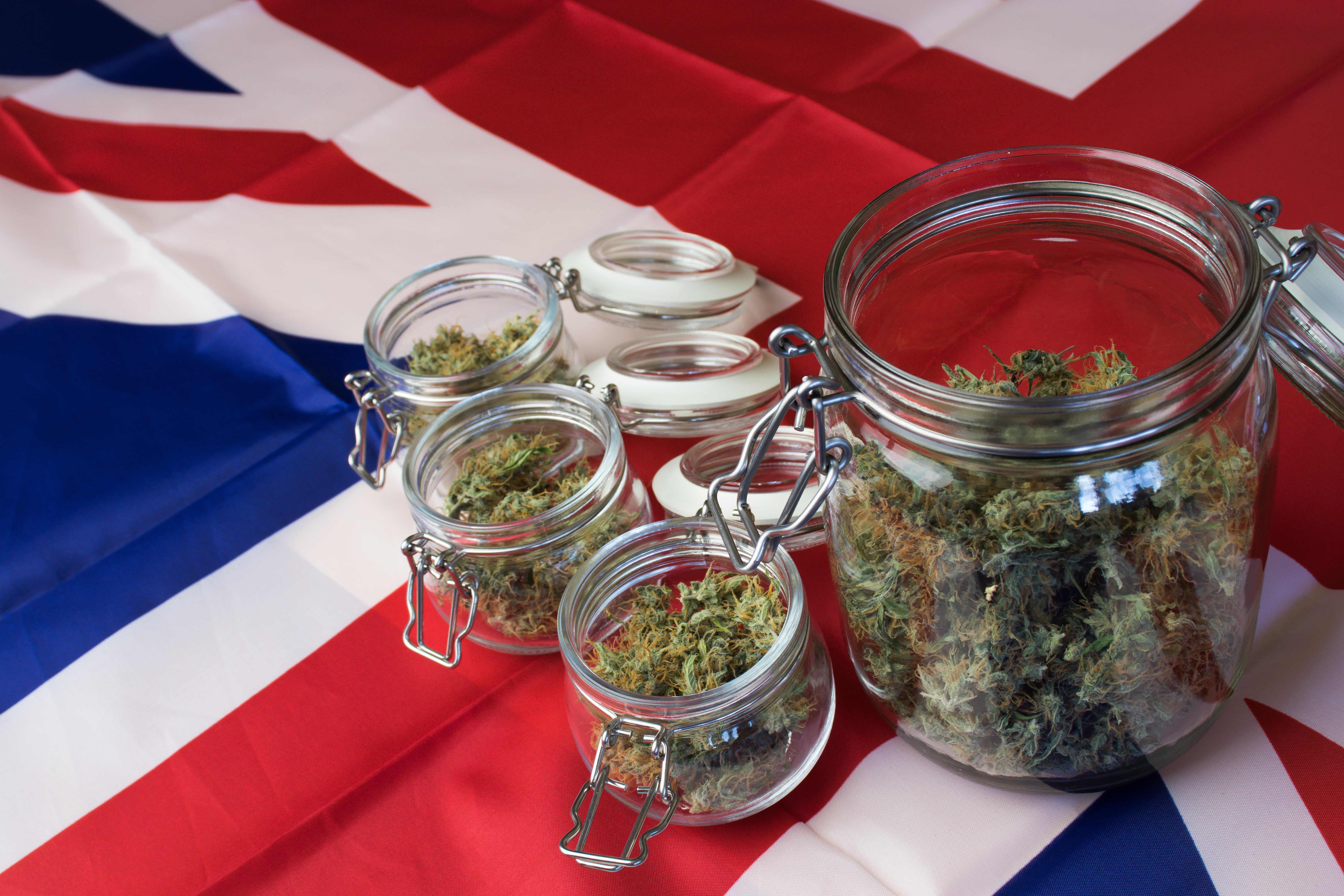 Jars of cannabis sit open on top of UK flag.
